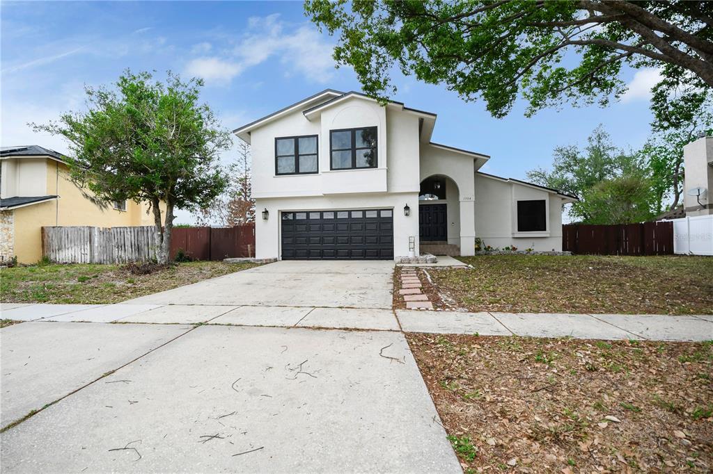 A two-story house with a white stucco exterior, black garage door, and a concrete driveway — 1304 ORTEGA STREET, WINTER SPRINGS, FL