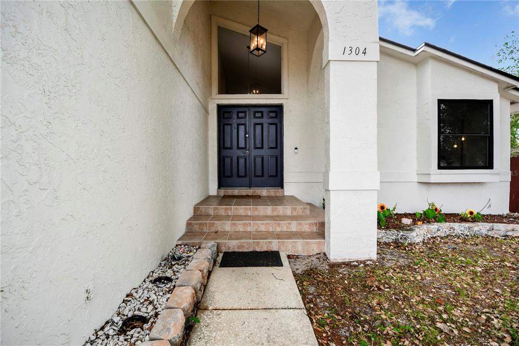 The exterior of a house features a tiled entryway, dark double doors, and white stucco walls — 1304 ORTEGA STREET, WINTER SPRINGS, FL