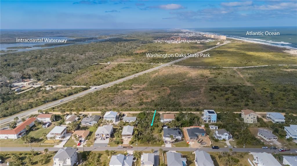 An aerial view shows a coastal neighborhood with a vacant lot marked by a blue arrow — 15 OCEAN STREET, PALM COAST, FL