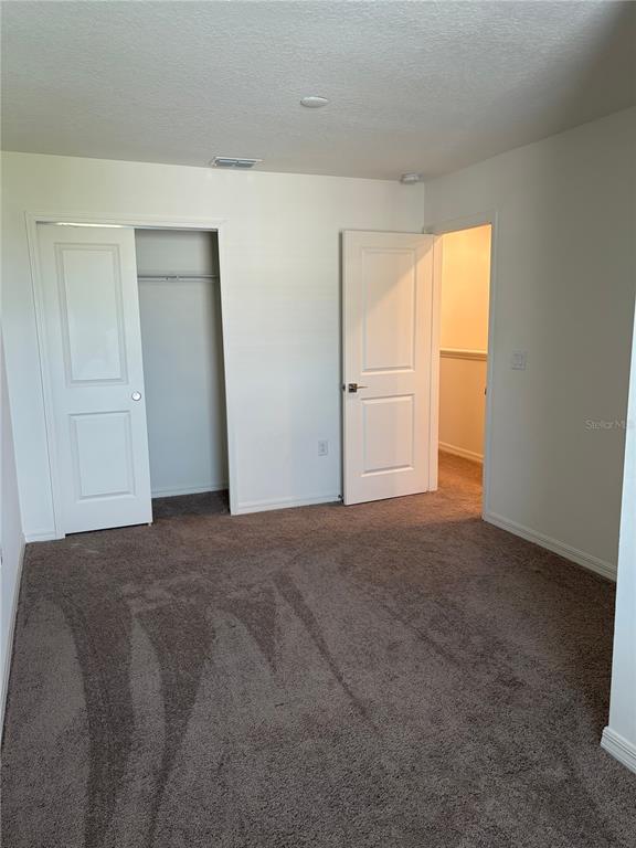 A bedroom with gray carpet, a sliding closet door, and an open doorway to a hallway — 1492 MIRABELLA CIRCLE, DAVENPORT, FL