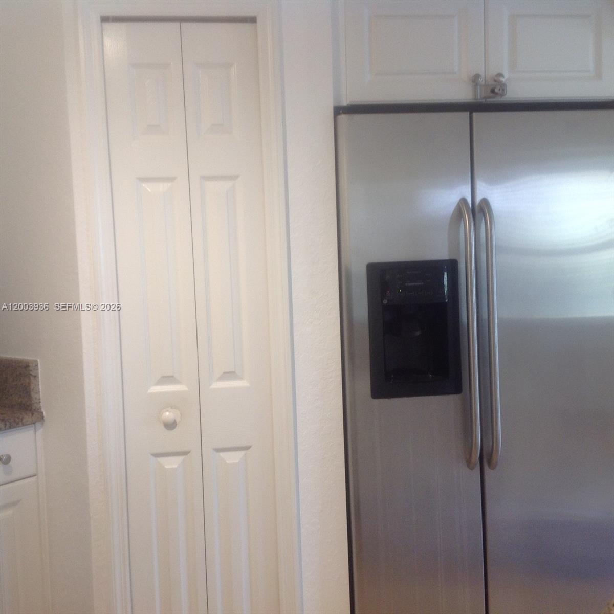 A stainless steel refrigerator stands next to a white bi-fold pantry door in a kitchen — 11401 NW 89th St # 105, Doral FL 33178, DORAL, FL