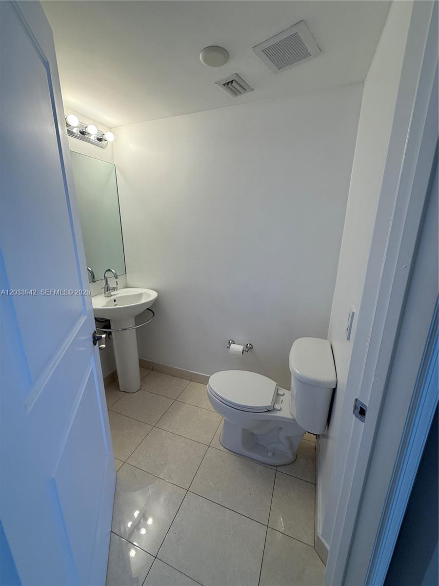 A small bathroom features a pedestal sink, a toilet, and light-colored tile flooring — 480 NE 30th St # 1504, Miami FL 33137, MIAMI, FL