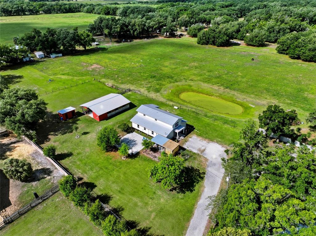 An aerial view shows a house, a red barn, and a pond on a rural property — 123 S WIGGINS ROAD, PLANT CITY, FL