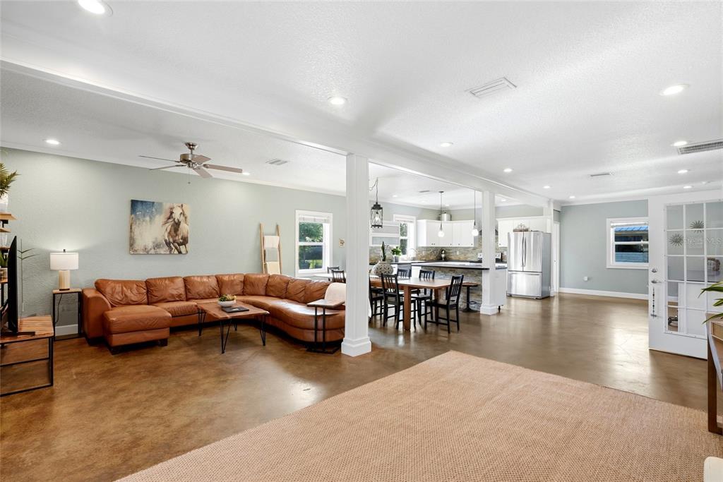 An open-concept living and dining area features a brown sectional sofa and concrete floors — 123 S WIGGINS ROAD, PLANT CITY, FL