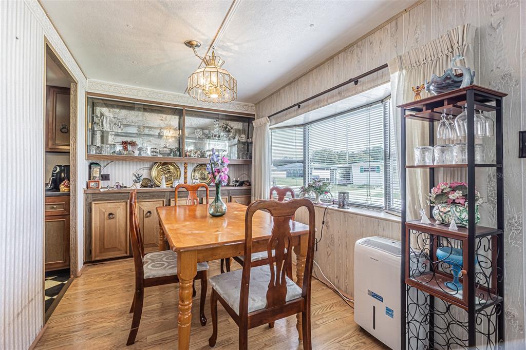 A dining room features wood-paneled walls, a wooden table with chairs, and a built-in hutch — 37544 ATTICA AVENUE, ZEPHYRHILLS, FL