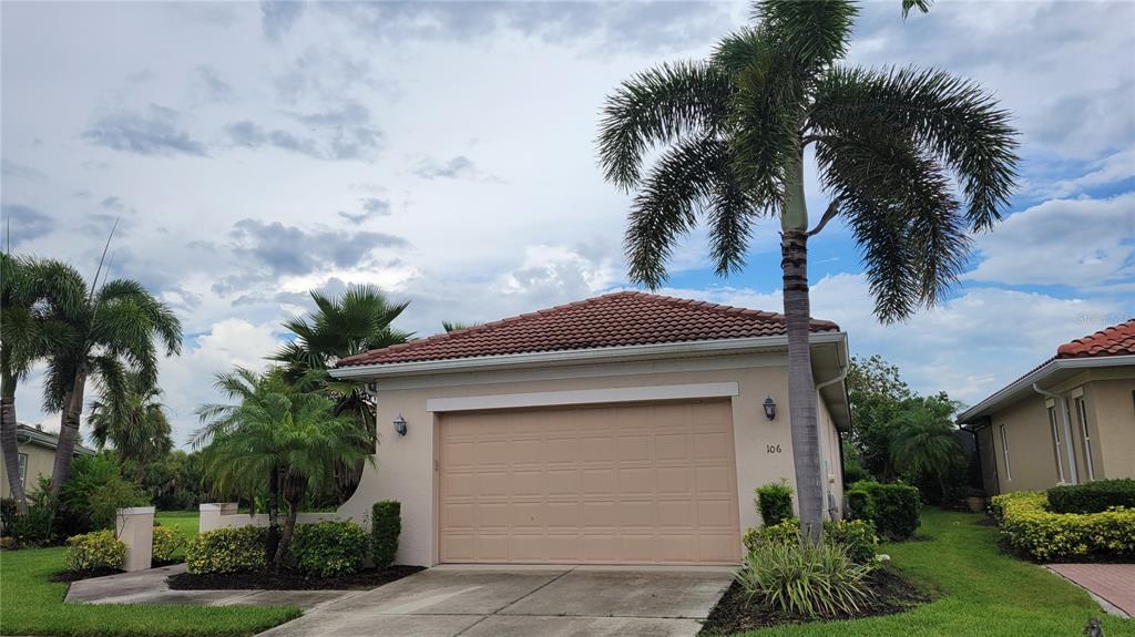 A beige garage with a tiled roof and a palm tree in the front yard — 106 LERIDA COURT, NOKOMIS, FL
