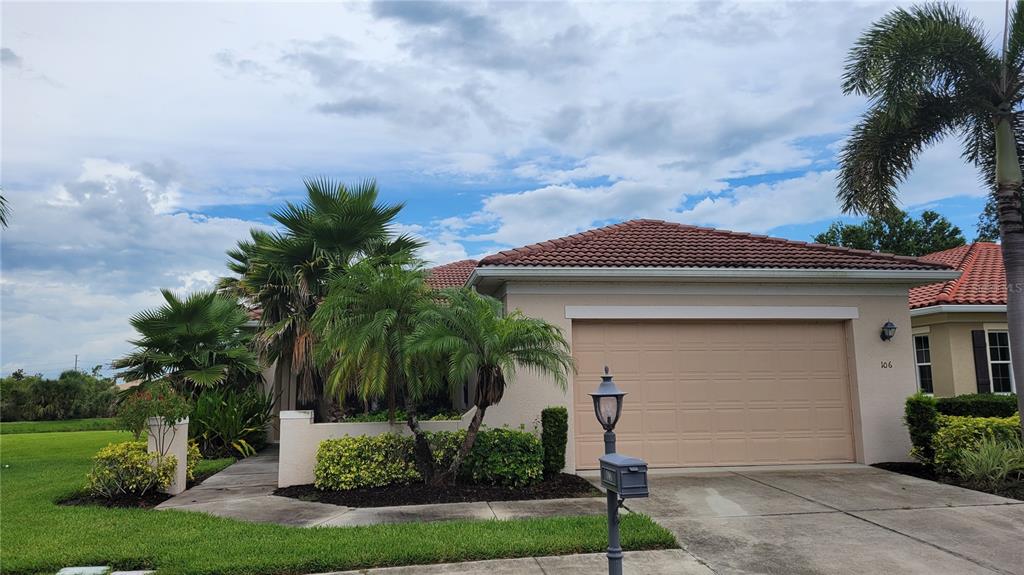 A single-story house with a beige stucco exterior, a tiled roof, and a two-car garage — 106 LERIDA COURT, NOKOMIS, FL