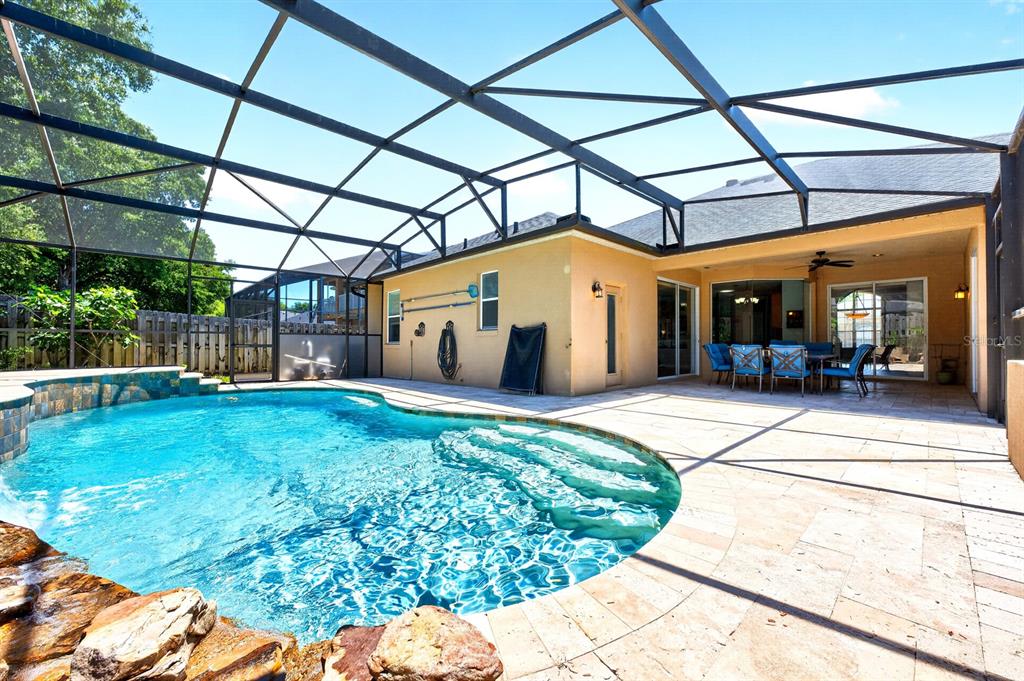 A screened-in patio features a swimming pool with a rock waterfall and outdoor dining area — 270 VIA RUSSO LANE, LAKE MARY, FL
