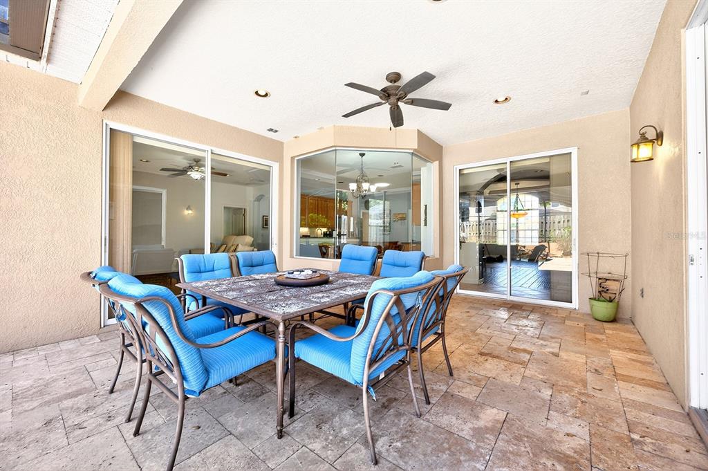 A covered patio features a dining set with blue cushions on a stone tile floor — 270 VIA RUSSO LANE, LAKE MARY, FL