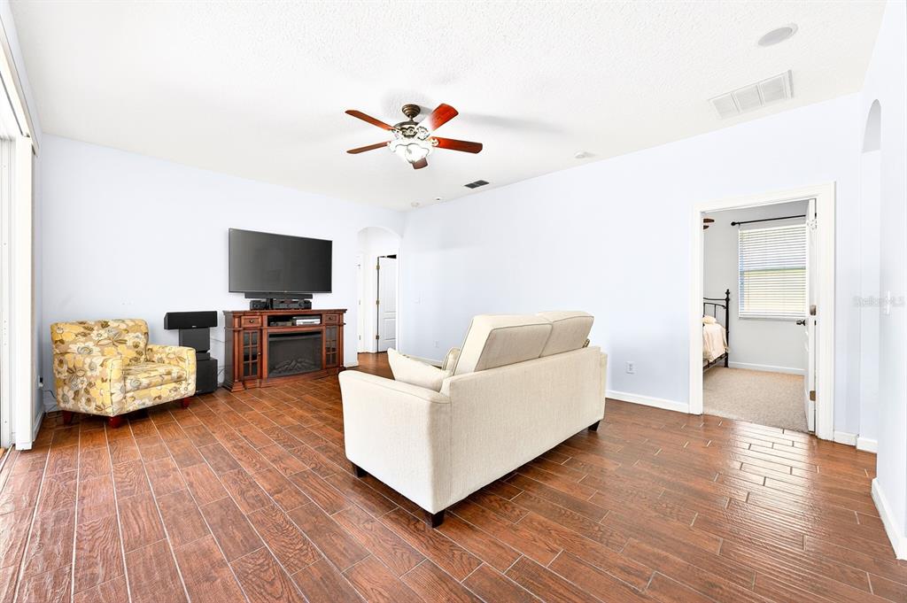 A living room features wood-look tile flooring, a beige sofa, a floral armchair, and a television — 270 VIA RUSSO LANE, LAKE MARY, FL