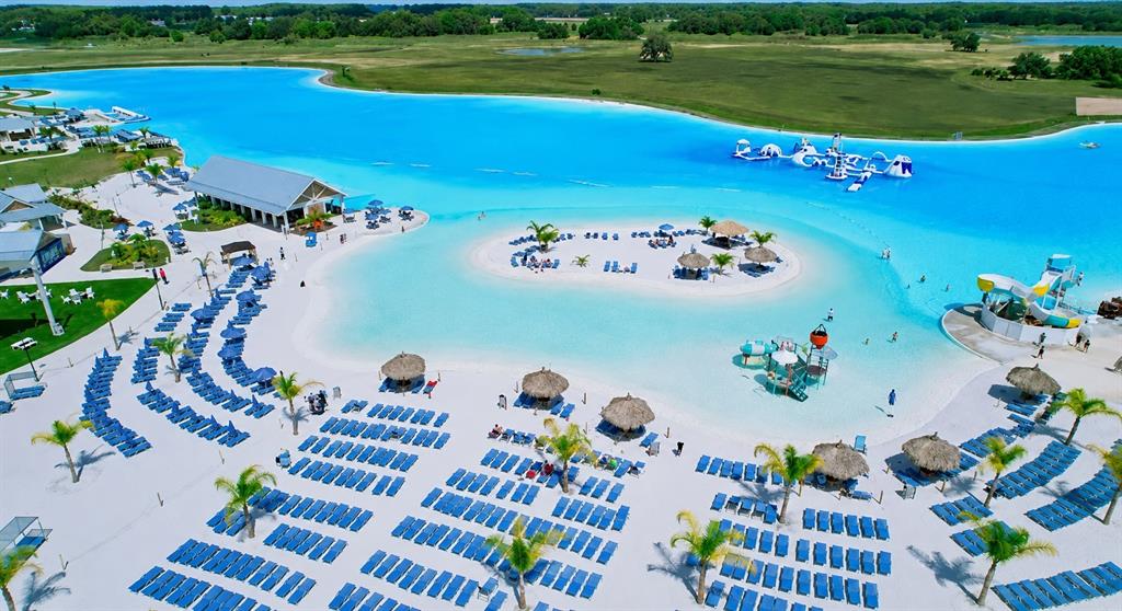 An aerial view shows a large turquoise lagoon with a sandy beach and lounge chairs — 10308 FIELDSTONE MYRTLE WAY, SAN ANTONIO, FL