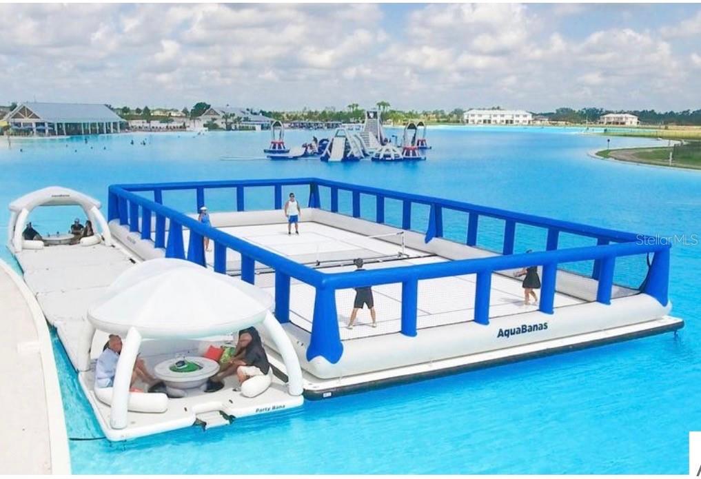 An inflatable floating court and lounge area sit on a large, bright blue lagoon — 10308 FIELDSTONE MYRTLE WAY, SAN ANTONIO, FL