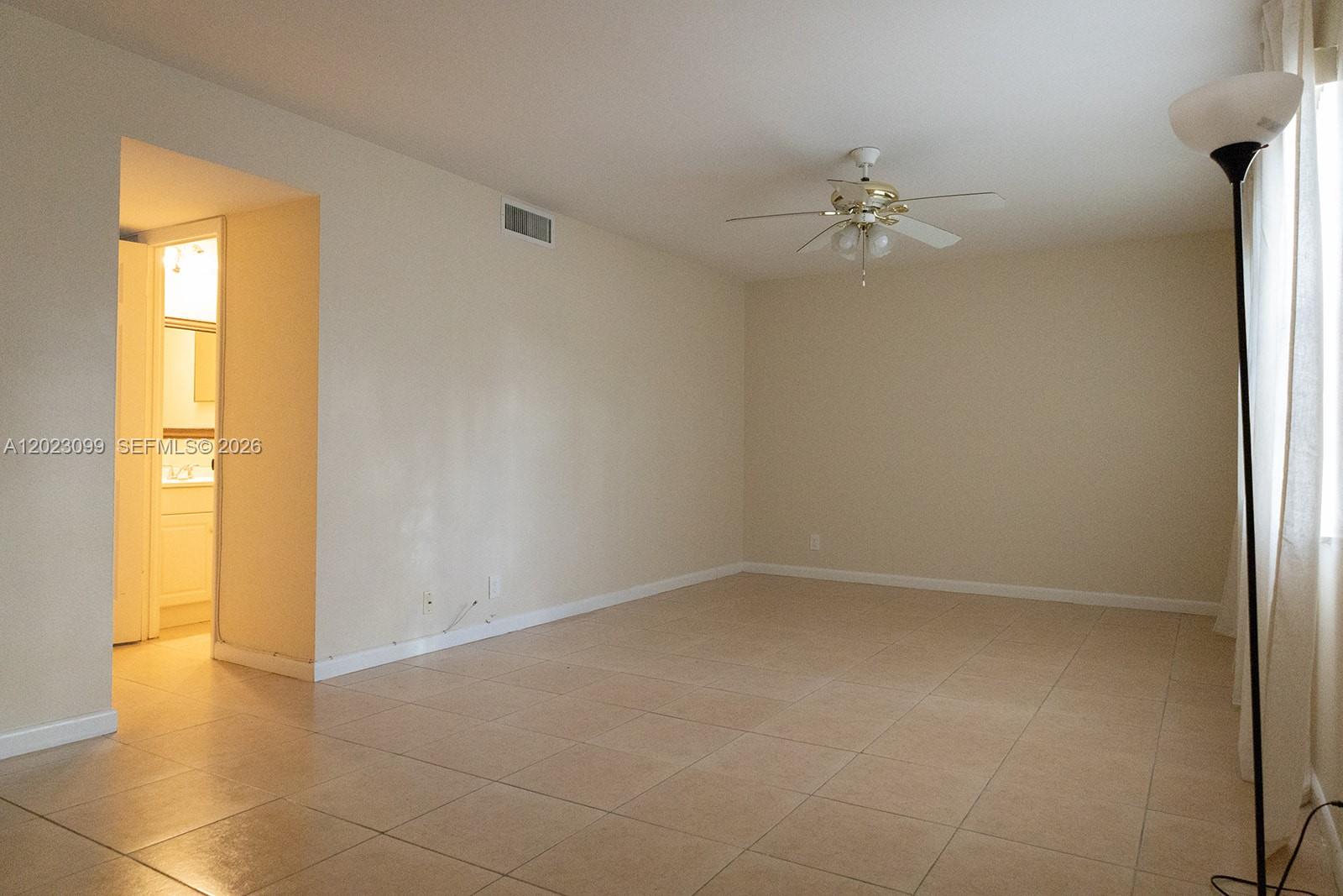 An empty room features beige tile flooring, a ceiling fan, and an adjacent bathroom doorway — 8018 SW 18th Ct # 8, Davie FL 33324, DAVIE, FL