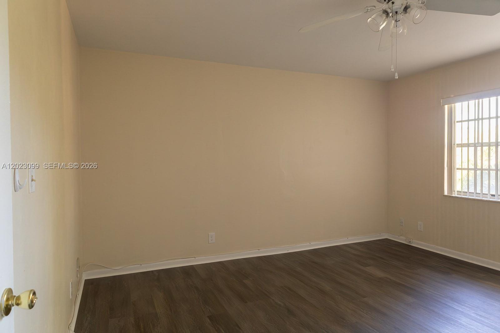 An empty bedroom features beige walls, dark wood-look flooring, and a ceiling fan — 8018 SW 18th Ct # 8, Davie FL 33324, DAVIE, FL