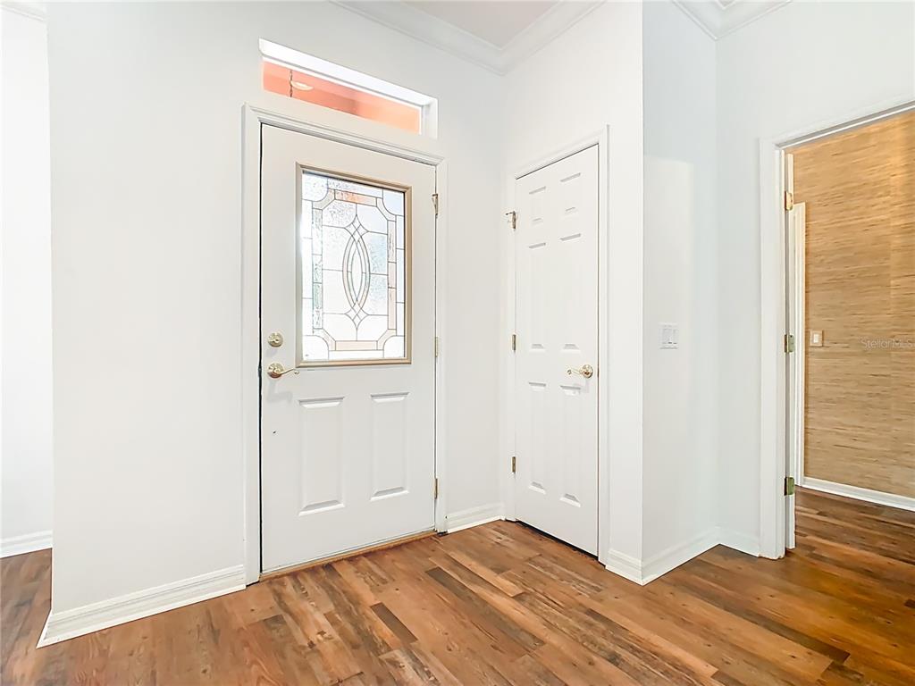 An entryway features a white front door with a glass insert, a closet, and wood flooring — 525 SHOREHAVEN  DRIVE, POINCIANA, FL