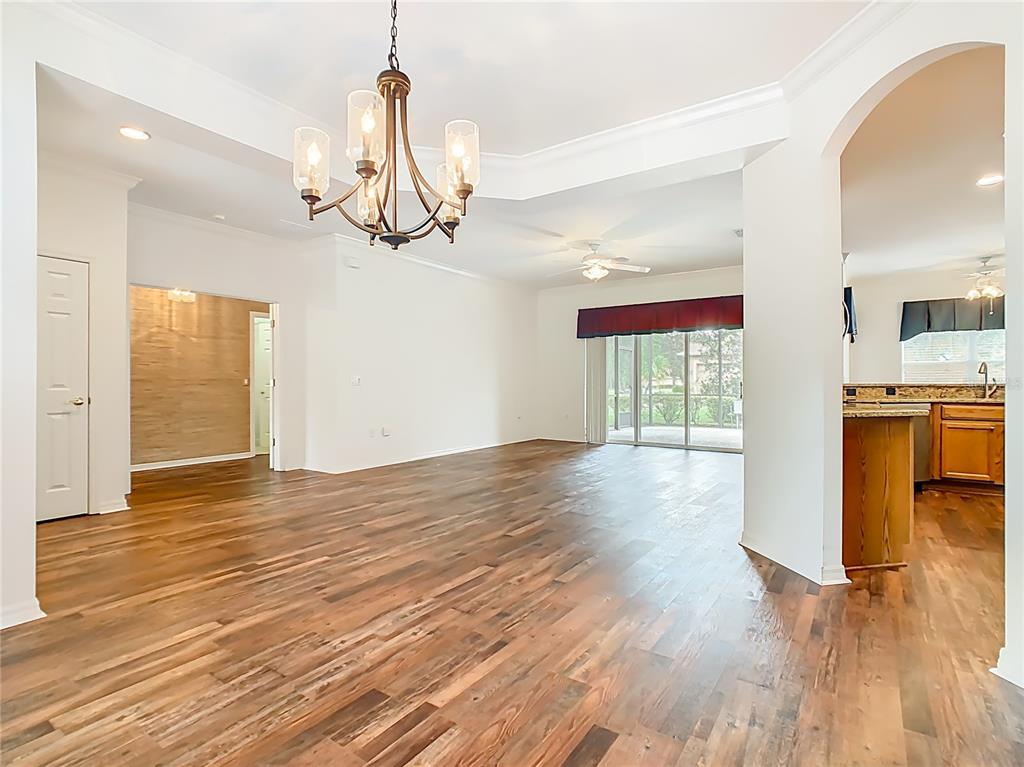 An open-concept living area features hardwood floors, a chandelier, and a view of the patio — 525 SHOREHAVEN  DRIVE, POINCIANA, FL