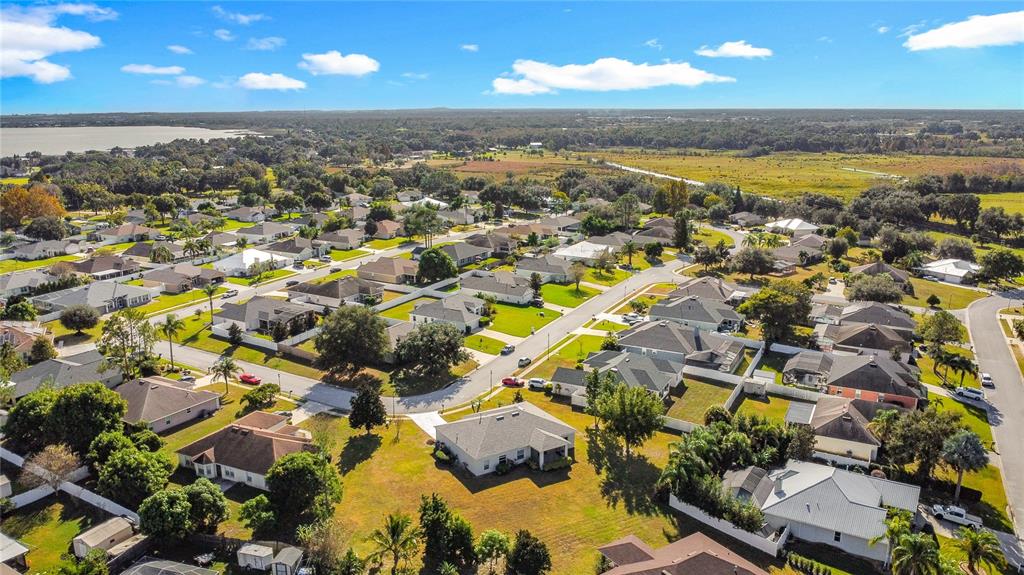 An aerial view shows a suburban neighborhood with single-family homes, green lawns, and distant wetlands — 312 TOWHEE ROAD, WINTER HAVEN, FL