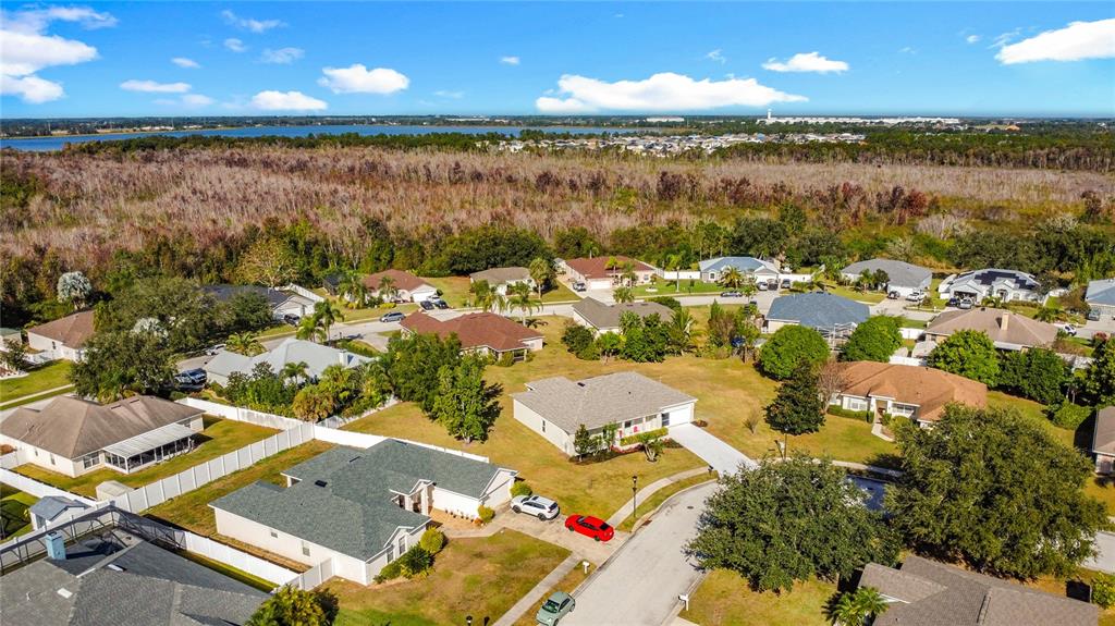 An aerial view shows a suburban neighborhood with single-family homes, green lawns, and surrounding vegetation — 312 TOWHEE ROAD, WINTER HAVEN, FL