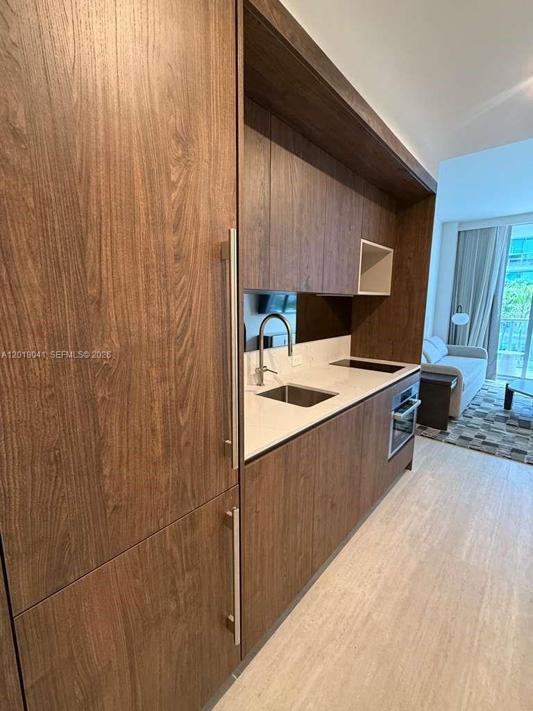 A modern kitchen features wood-grain cabinetry, white countertops, and a built-in oven — 1611 SW 2nd ave # 510, Miami FL 33129, MIAMI, FL
