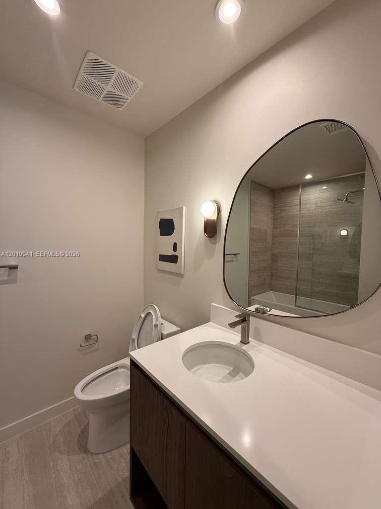 A modern bathroom features a vanity with a white countertop, an irregular mirror, and toilet — 1611 SW 2nd ave # 510, Miami FL 33129, MIAMI, FL