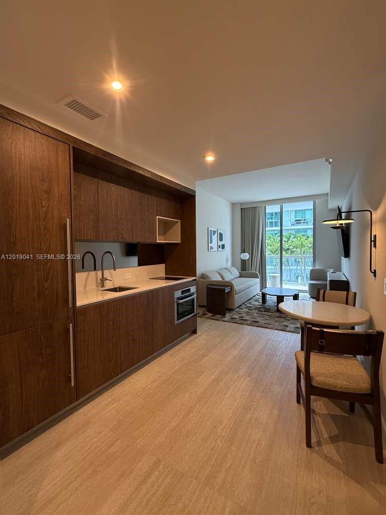 A modern studio apartment features a kitchenette with wood cabinetry, a dining area, and living space — 1611 SW 2nd ave # 510, Miami FL 33129, MIAMI, FL