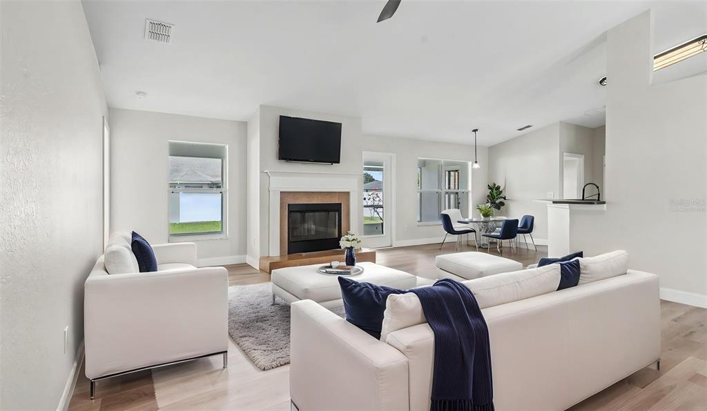 A bright living room features a fireplace, white sofas, and an adjacent dining area — 530 BUCKSHOT LANE, LAKELAND, FL