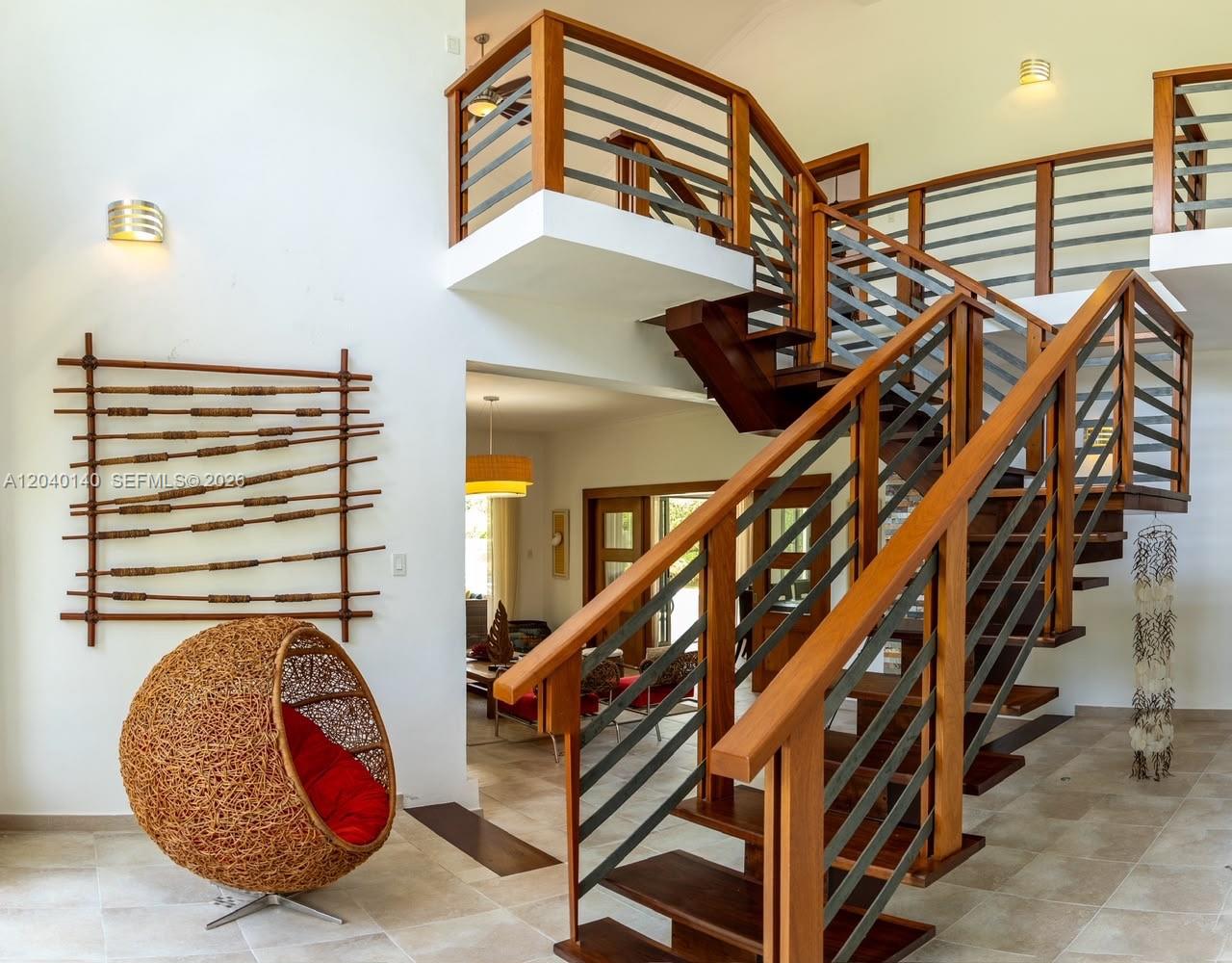 A modern staircase with wooden treads and metal railings stands in a bright, open-plan room — 0 juan dolio, 0, FL