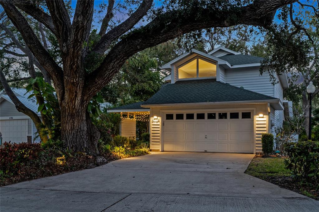 A two-story house with a white garage and a large tree in the front yard — 6704 ARBOR OAKS DRIVE, BRADENTON, FL