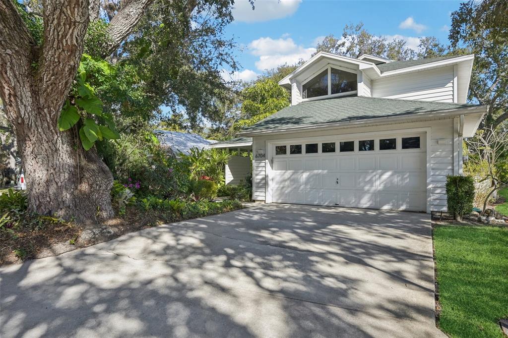 A two-story house with white siding, a green roof, and a concrete driveway — 6704 ARBOR OAKS DRIVE, BRADENTON, FL