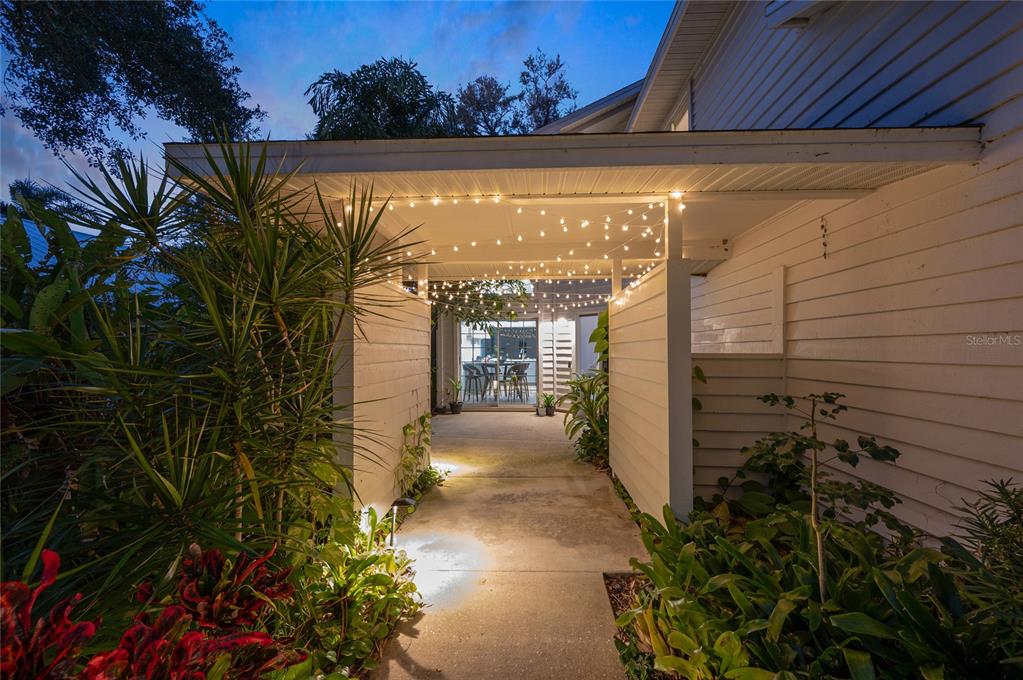 A covered walkway with string lights leads to a patio area with outdoor furniture — 6704 ARBOR OAKS DRIVE, BRADENTON, FL