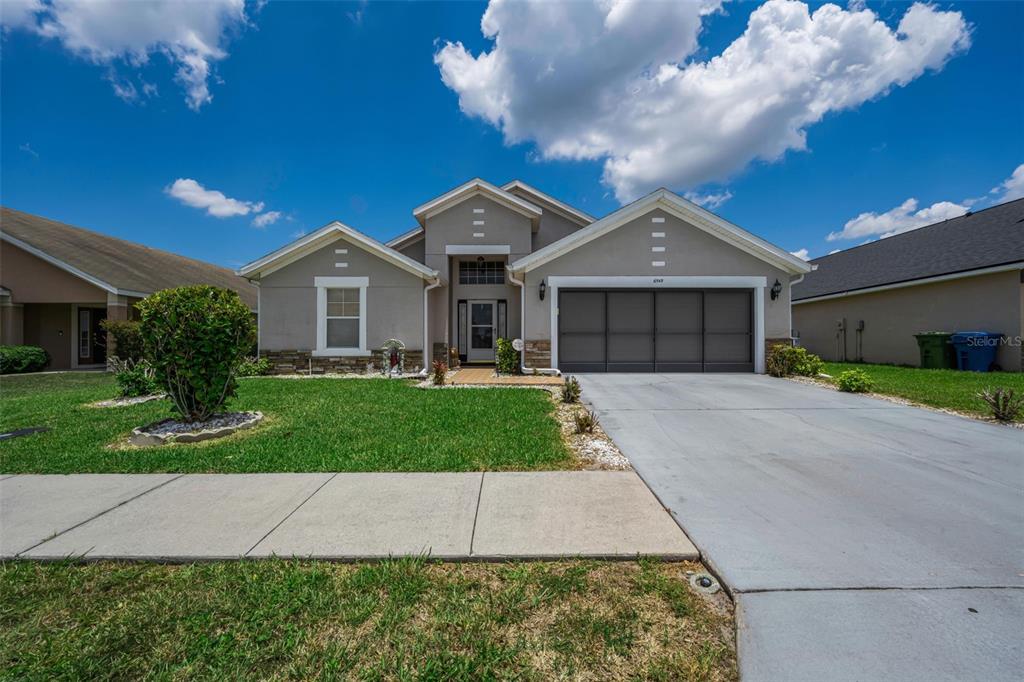 A single-story suburban house with a gray exterior, a two-car garage, and a front lawn — 6549 CRESCENT LOOP, WINTER HAVEN, FL
