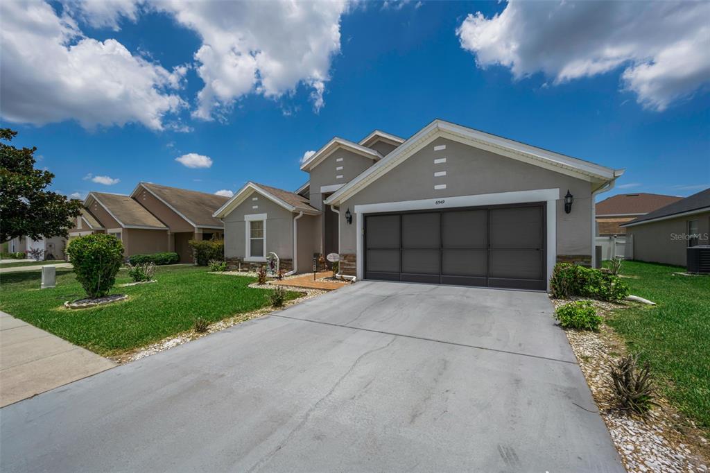 A single-story suburban house with a gray exterior, a two-car garage, and a concrete driveway — 6549 CRESCENT LOOP, WINTER HAVEN, FL