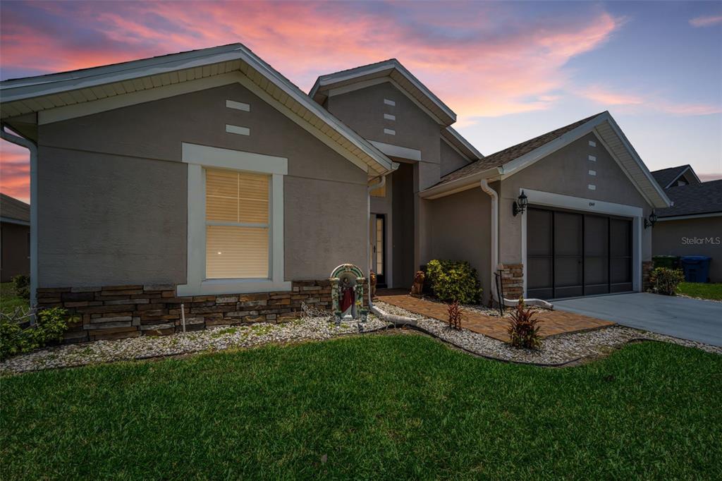A single-story house with a stone veneer base, a garage, and a landscaped front yard — 6549 CRESCENT LOOP, WINTER HAVEN, FL