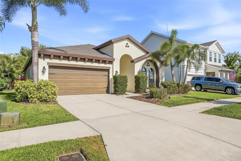 A single-story house with a tan stucco exterior, a brown garage door, and palm trees — 6318 SPRINGLINE PLACE, APOLLO BEACH, FL
