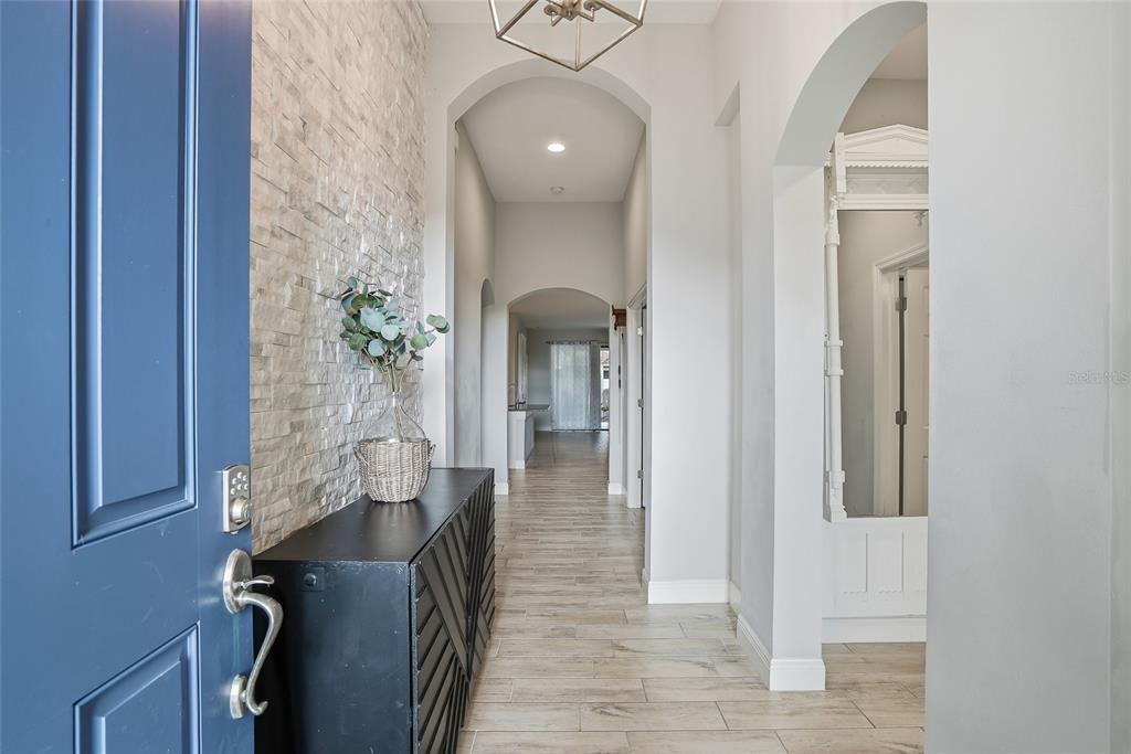 A foyer with a blue door, stone accent wall, black console table, and arched hallways — 6318 SPRINGLINE PLACE, APOLLO BEACH, FL