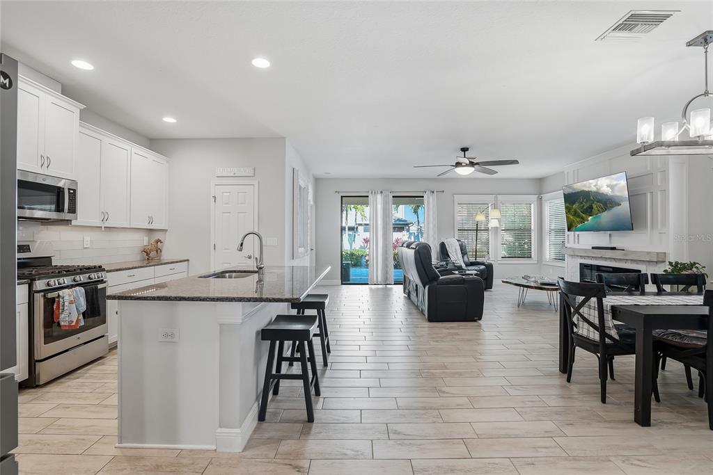 An open-concept kitchen and living area features white cabinetry, a granite island, and tile flooring — 6318 SPRINGLINE PLACE, APOLLO BEACH, FL