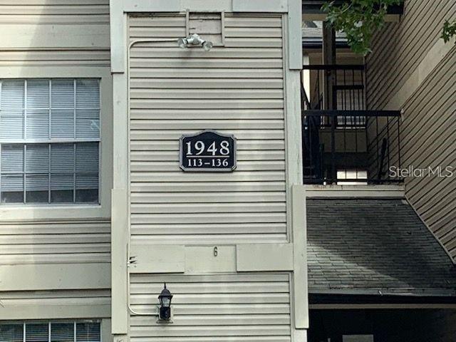 The exterior of a multi-story apartment building features beige siding and a unit number sign — 1948 LAKE ATRIUMS CIRCLE UNIT 115, ORLANDO, FL