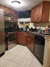 A kitchen with wood cabinets, stainless steel appliances, and light-colored tile flooring — 1948 LAKE ATRIUMS CIRCLE UNIT 115, ORLANDO, FL