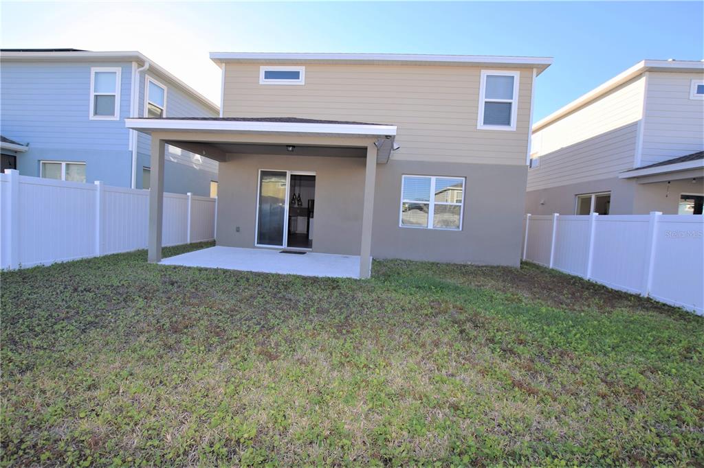 The exterior of a two-story house features a covered patio and a fenced backyard — 4358 SILVER CREEK STREET, KISSIMMEE, FL