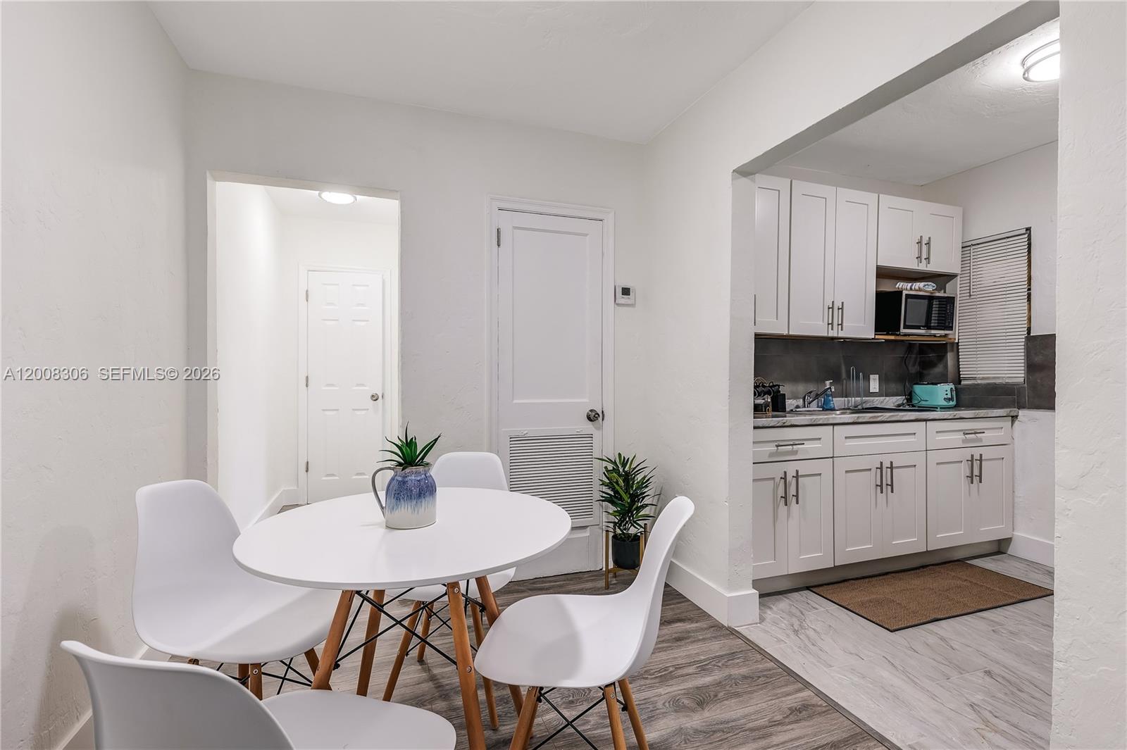 A dining area with a round table and chairs sits adjacent to a white kitchen — 327 NE 55th St # 2, Miami FL 33137, MIAMI, FL