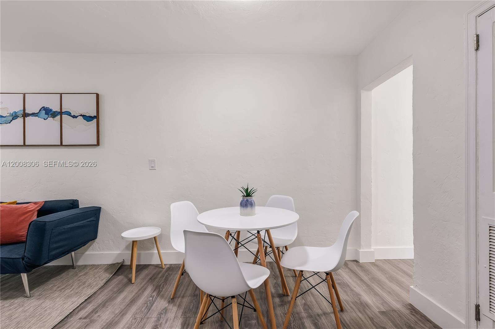 A dining area features a white round table, four white chairs, and wood-look flooring — 327 NE 55th St # 2, Miami FL 33137, MIAMI, FL