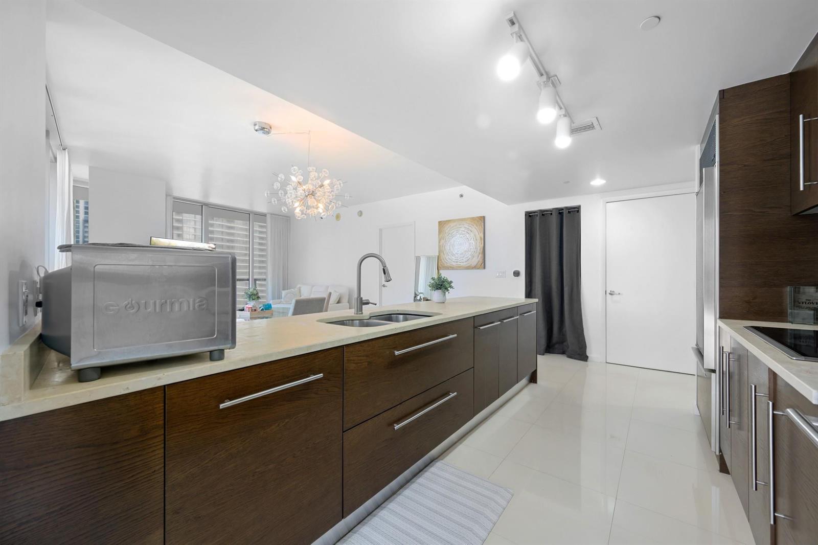 A modern kitchen features dark wood cabinets, light countertops, and stainless steel appliances — 475 Brickell Avenue # 1815, Miami FL 33131, MIAMI, FL