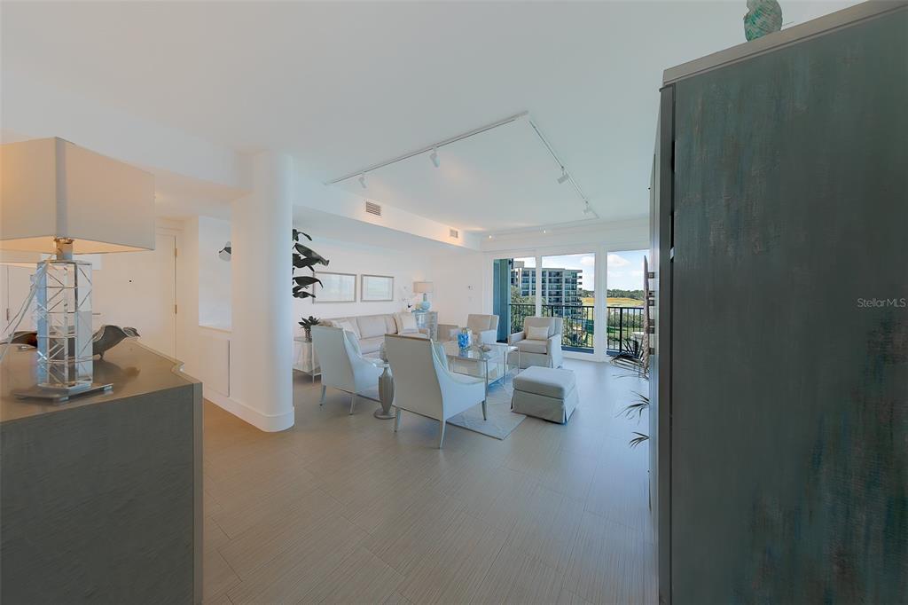 A bright living room features light wood-look flooring, neutral furniture, and a balcony with views — 8 BELLEVIEW BOULEVARD UNIT 507, BELLEAIR, FL