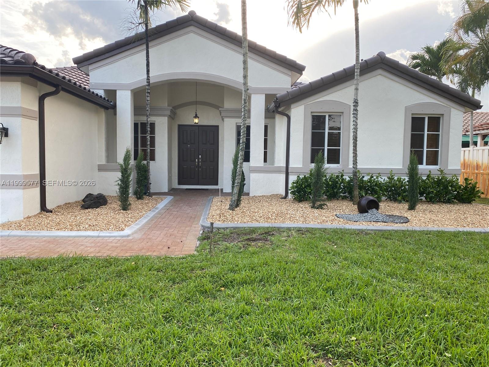 The exterior of a single-story house features a paved walkway, gravel landscaping, and palm trees — 4000 SW 145th Ave, Miramar FL 33027, MIRAMAR, FL