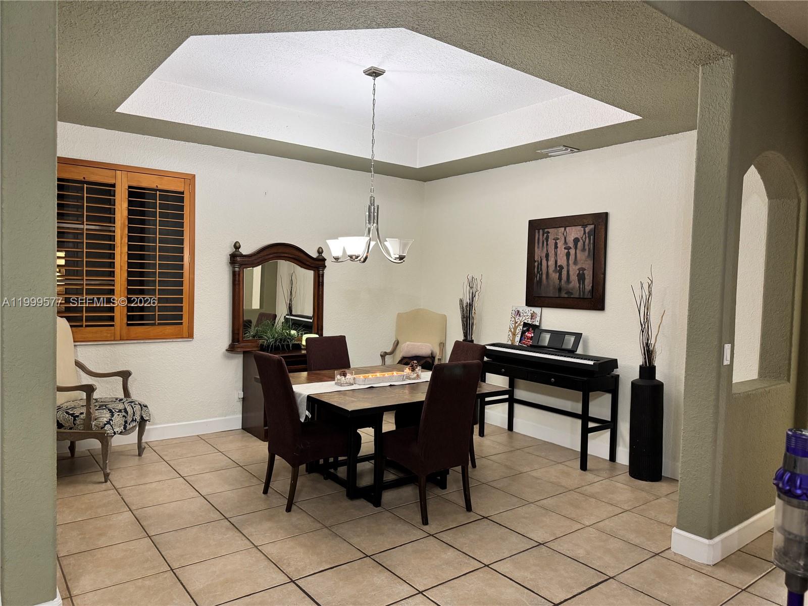 A dining room features a tray ceiling, tile flooring, and a dark wood table set — 4000 SW 145th Ave, Miramar FL 33027, MIRAMAR, FL