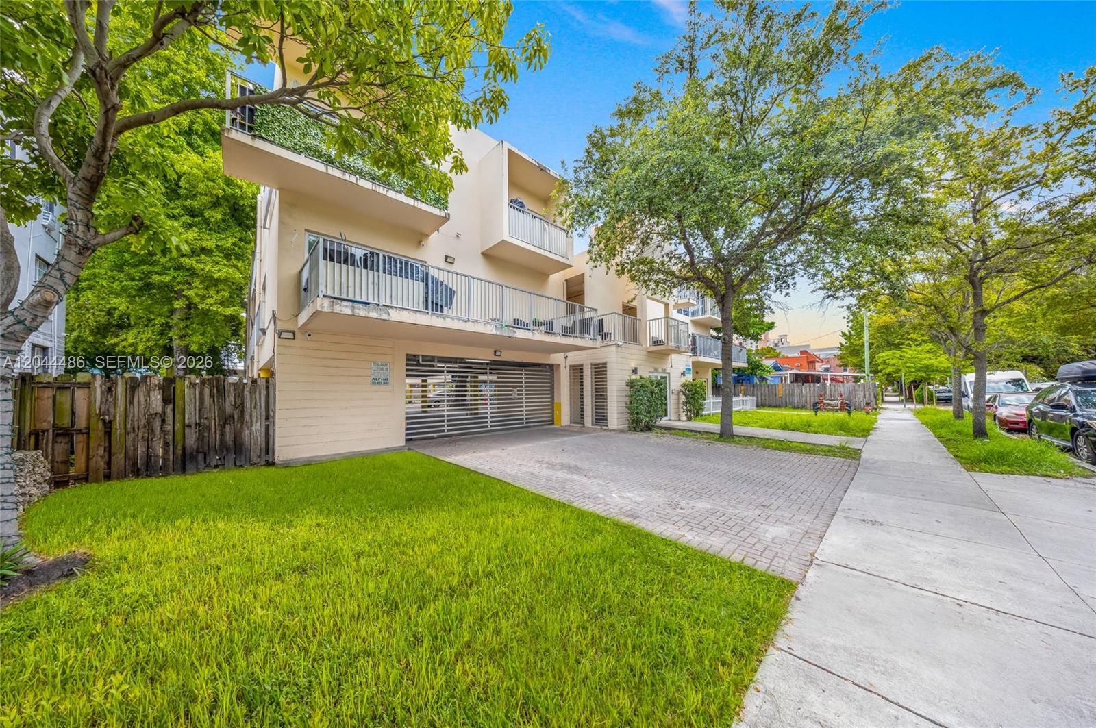 A three-story apartment building features a ground-level parking garage, balconies, and a paved driveway — 1553 SW 2nd St, Miami FL 33135, MIAMI, FL