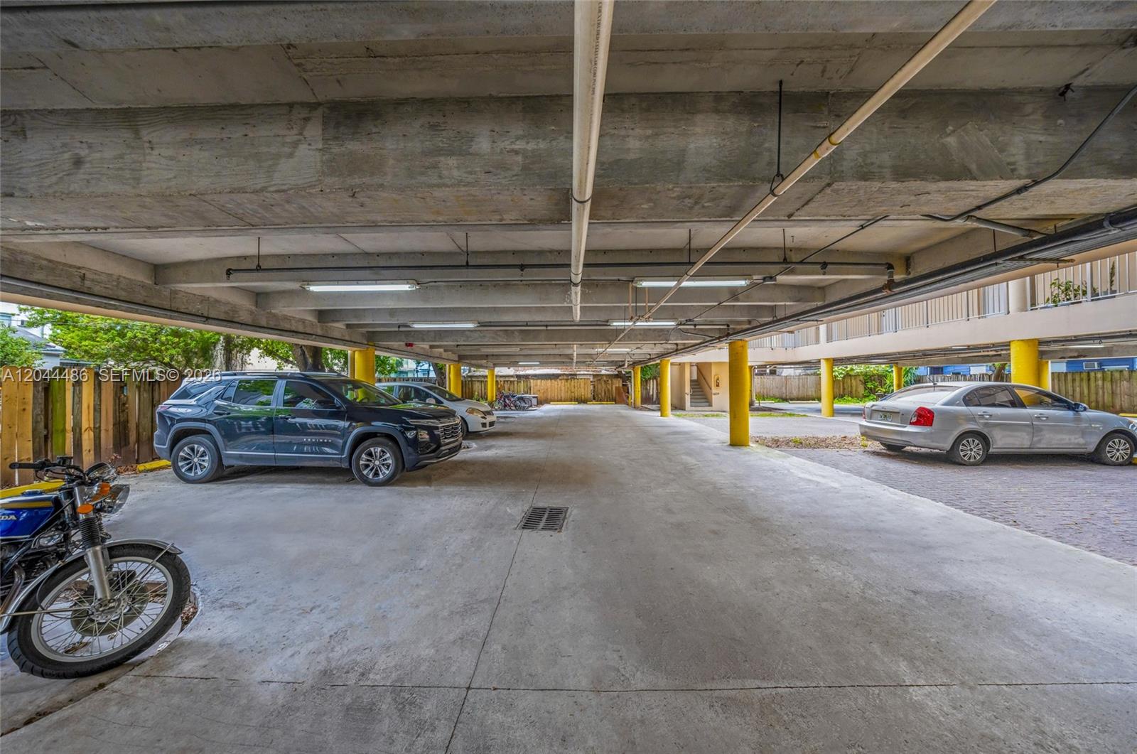 A covered parking garage features concrete ceilings, yellow support columns, and several parked vehicles — 1553 SW 2nd St, Miami FL 33135, MIAMI, FL