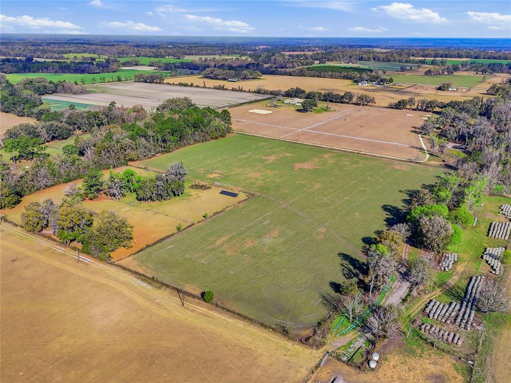 An aerial view shows a large, open grassy field surrounded by trees and farmland — TBD NW COUNTY ROAD 239, ALACHUA, FL