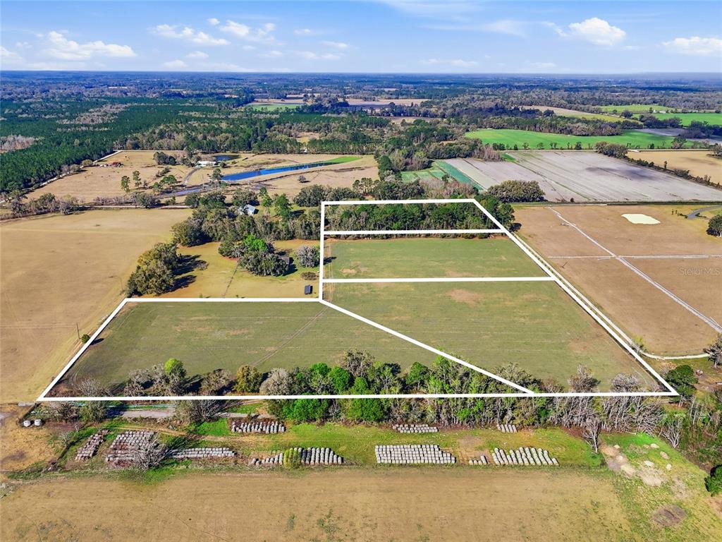 An aerial view shows a large, fenced plot of rural land with grassy fields — TBD NW COUNTY ROAD 239, ALACHUA, FL