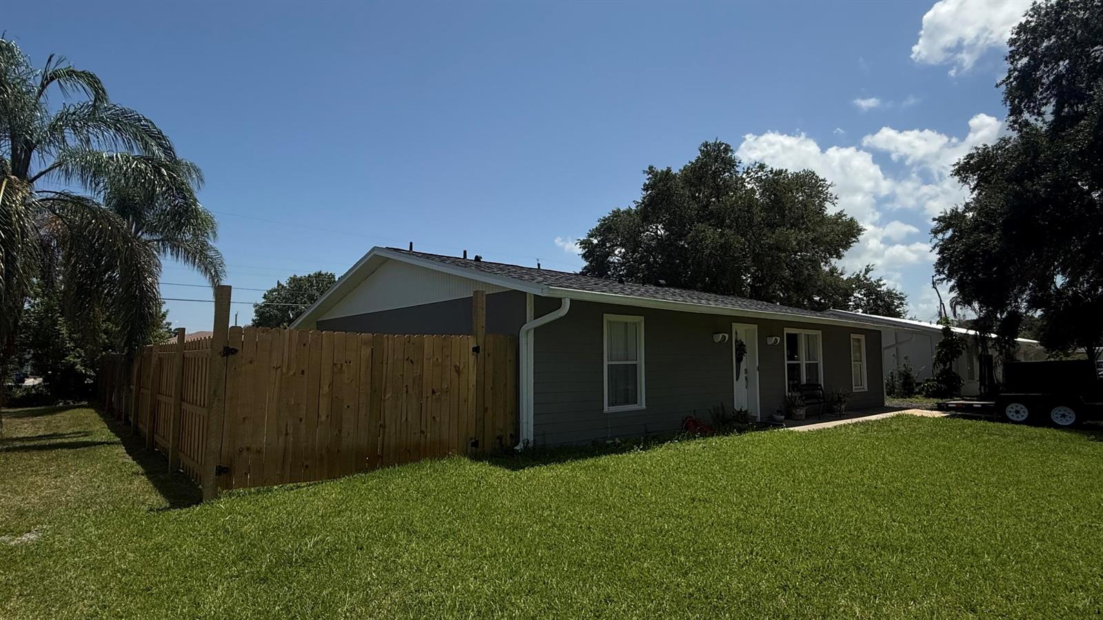 A kitchen features white cabinets, quartz countertops, a kitchen island with a cooktop, and wood-look flooring — 433 20th Street SW, Vero Beach FL 32962, VERO BEACH, FL